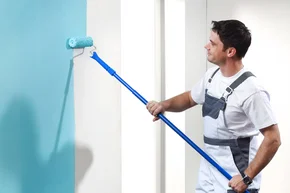 Malerarbeiten - Decor-Union Service 006a Maler streicht Wand mit blauer Farbe